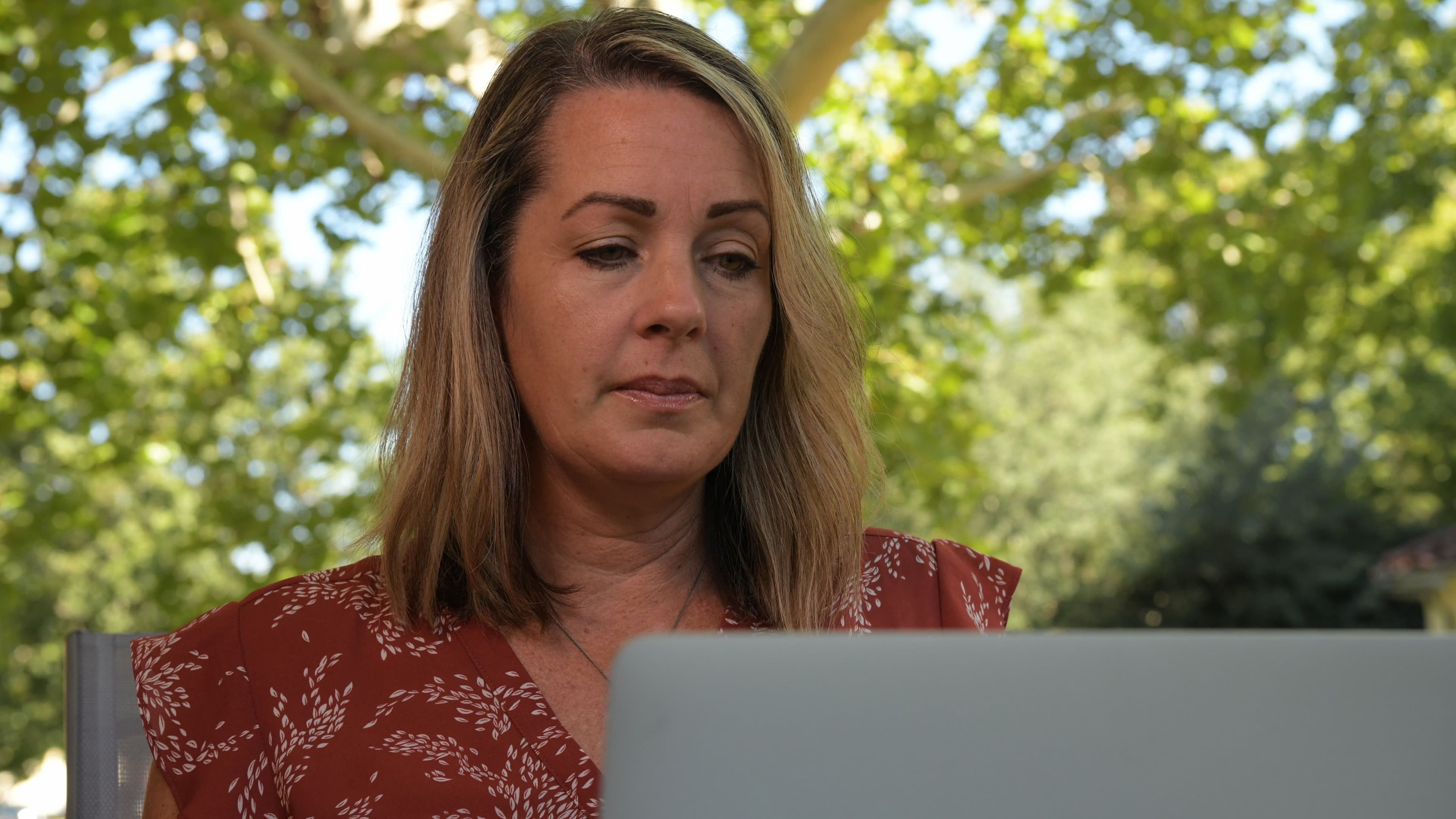A woman works on her laptop outdoors.